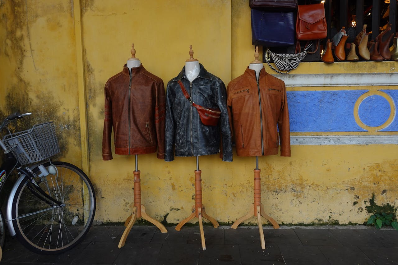 Three leather jackets on mannequins against a vibrant yellow wall.